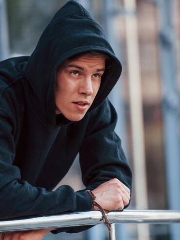 hoodie manufacturer USA a man standing on terrace wearing a black hoodie manufactured by clothingmanufacturer.us for wholesale clients