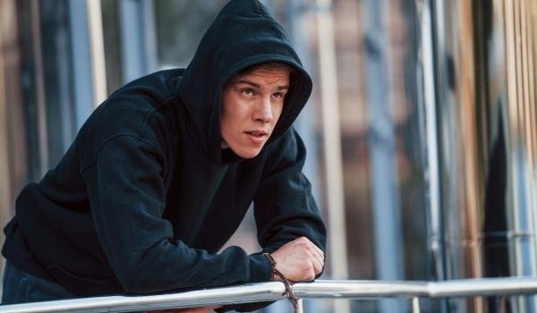 Hoodie Manufacturer Usa 11 hoodie manufacturer USA a man standing on terrace wearing a black hoodie manufactured by clothingmanufacturer.us for wholesale clients